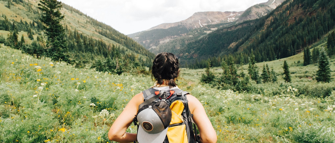 Solo traveler with backpack standing on a scenic mountain overlook